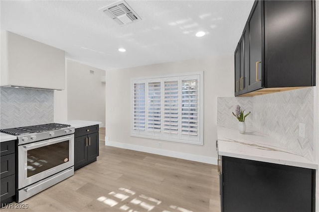 kitchen featuring light hardwood / wood-style flooring, decorative backsplash, stainless steel range with gas cooktop, and light stone countertops