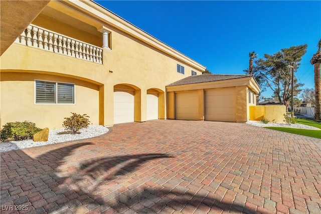 view of side of home with a garage and a balcony