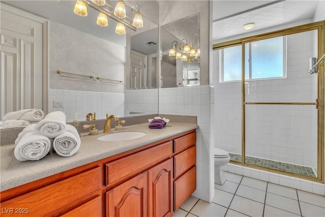 bathroom with tile walls, vanity, an enclosed shower, tile patterned floors, and toilet