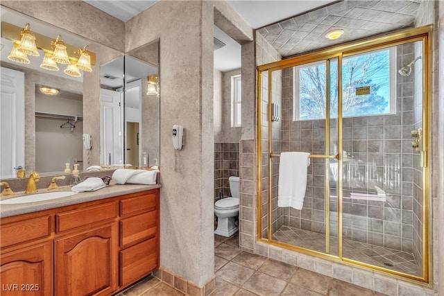 bathroom with vanity, a shower with shower door, tile patterned floors, and toilet