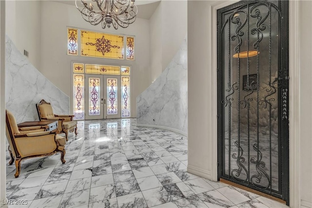 foyer entrance featuring a high ceiling, an inviting chandelier, and french doors