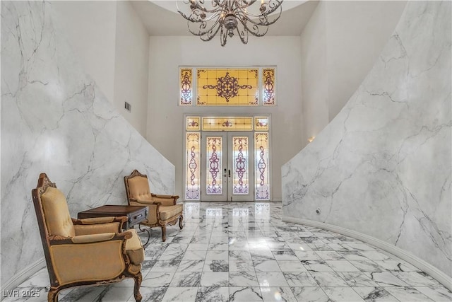 foyer entrance with a towering ceiling, an inviting chandelier, and french doors