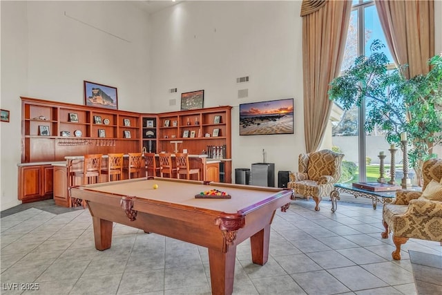 rec room with pool table, bar area, a towering ceiling, and light tile patterned floors