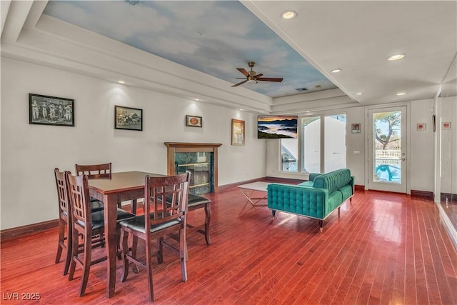 dining area featuring a tray ceiling, a premium fireplace, and hardwood / wood-style flooring