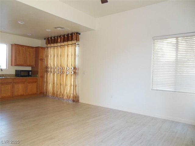 interior space with ceiling fan, sink, and light hardwood / wood-style floors