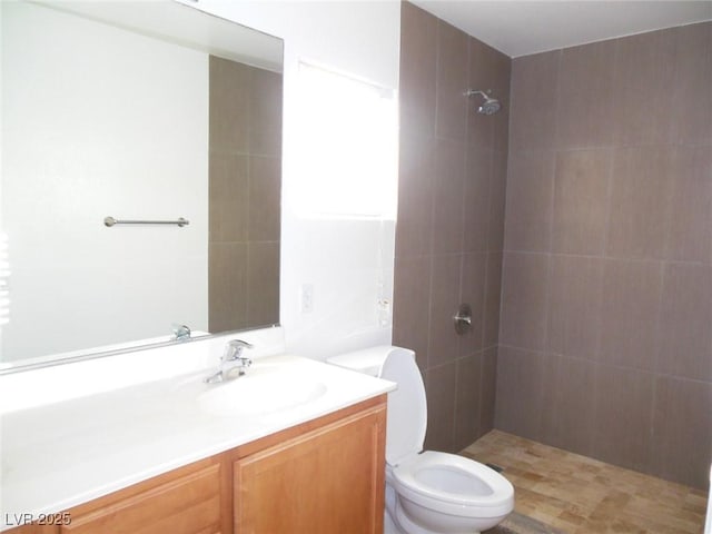 bathroom featuring vanity, a tile shower, and toilet