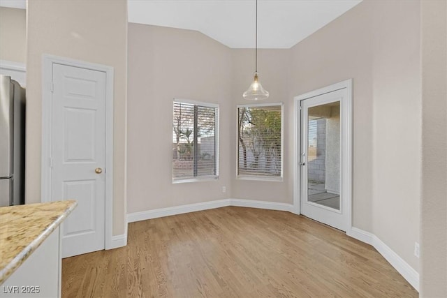 unfurnished dining area with lofted ceiling and light hardwood / wood-style floors