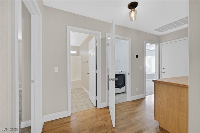 corridor with washer / dryer and light wood-type flooring