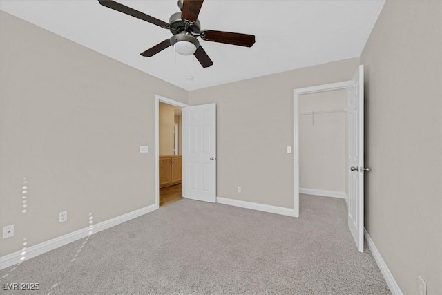 unfurnished bedroom with ceiling fan, a walk in closet, a closet, and light carpet