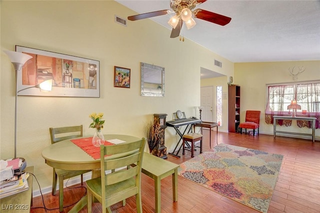 dining space with ceiling fan, vaulted ceiling, and wood-type flooring