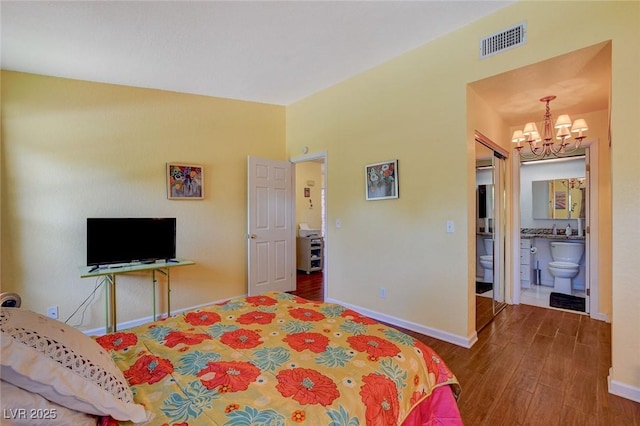 bedroom with a notable chandelier, dark hardwood / wood-style flooring, and ensuite bath