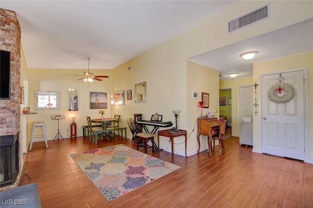 foyer entrance with hardwood / wood-style flooring, vaulted ceiling, ceiling fan, and a fireplace