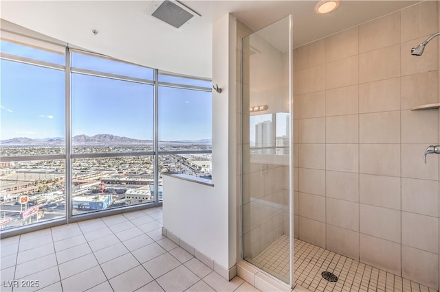 bathroom with an enclosed shower, a mountain view, a wall of windows, and tile patterned floors