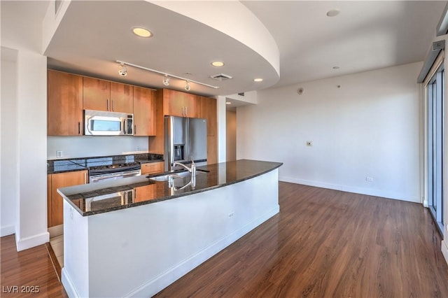 kitchen featuring stainless steel appliances, dark hardwood / wood-style flooring, sink, and a center island with sink
