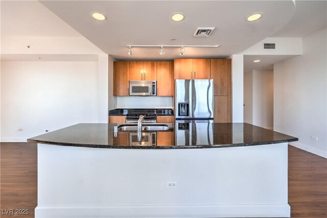 kitchen featuring stainless steel appliances, an island with sink, sink, and dark wood-type flooring