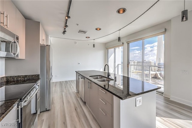 200 W Sahara Ave Unit 2108, Las Vegas, NV 89102 - kitchen featuring a sink, light wood-style flooring, stainless steel appliances, a kitchen island with sink, and dark stone countertops