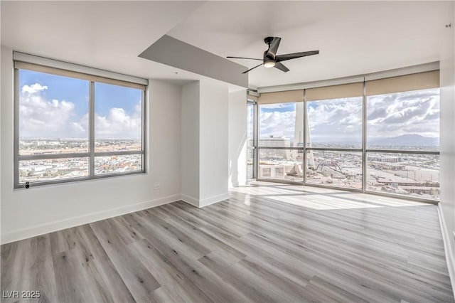 200 W Sahara Ave Unit 2108, Las Vegas, NV 89102 - empty room featuring a ceiling fan, expansive windows, wood finished floors, and baseboards