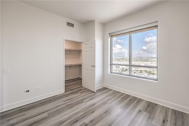 200 W Sahara Ave Unit 2108, Las Vegas, NV 89102 - unfurnished bedroom featuring light wood-type flooring, baseboards, a closet, and a walk in closet