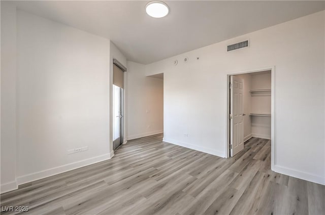 200 W Sahara Ave Unit 2108, Las Vegas, NV 89102 - unfurnished bedroom featuring light wood-style floors, baseboards, a walk in closet, and a closet