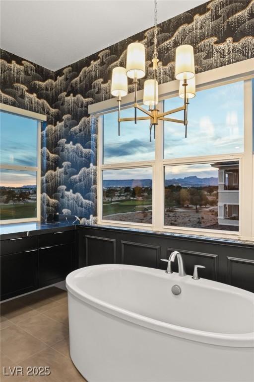 bathroom featuring tile patterned flooring, a bathtub, and an inviting chandelier