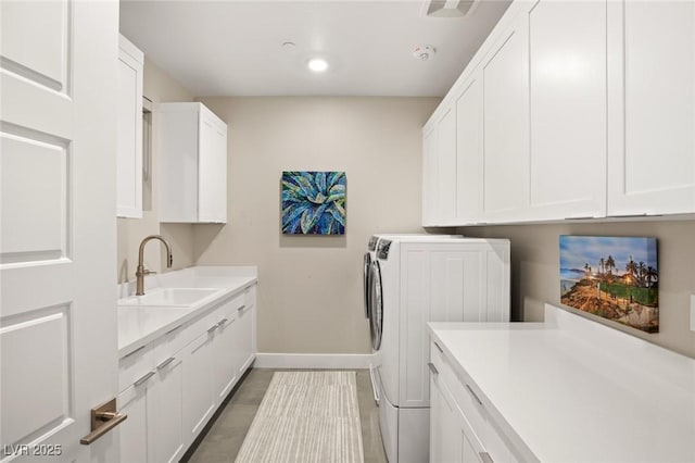 clothes washing area with cabinets, separate washer and dryer, and sink