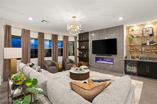 living room with a premium fireplace, beverage cooler, indoor wet bar, and a notable chandelier