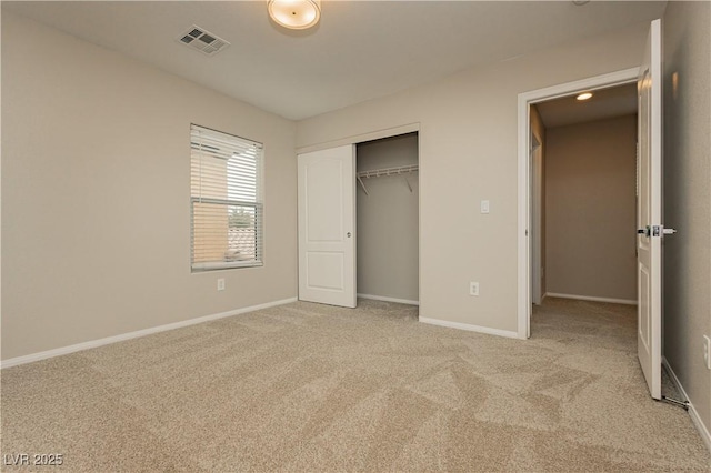 unfurnished bedroom with light colored carpet and a closet