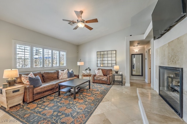 tiled living room featuring vaulted ceiling, a tile fireplace, and ceiling fan