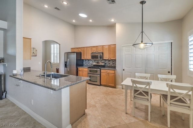 kitchen with sink, decorative light fixtures, dark stone countertops, kitchen peninsula, and stainless steel appliances