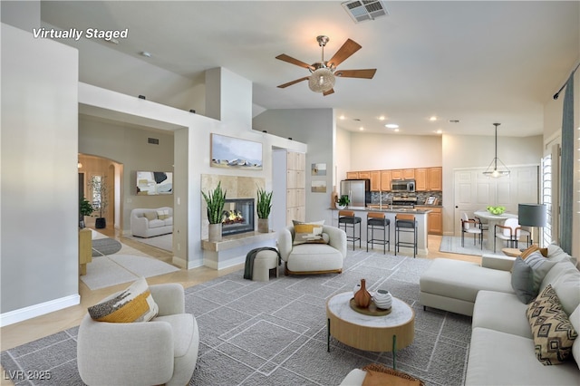 living room featuring a tiled fireplace and high vaulted ceiling