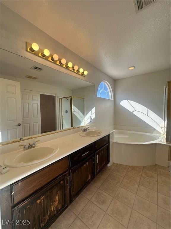 bathroom featuring tile patterned floors, plus walk in shower, vanity, and a textured ceiling