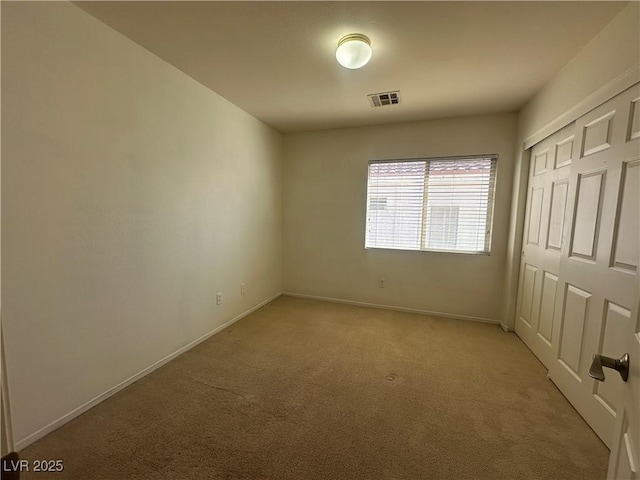 unfurnished bedroom with light colored carpet and a closet