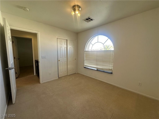 unfurnished bedroom with light colored carpet and a closet