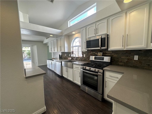 kitchen featuring lofted ceiling, white cabinetry, tasteful backsplash, appliances with stainless steel finishes, and dark hardwood / wood-style flooring