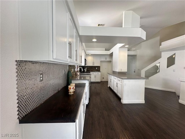 kitchen with dark wood-type flooring, sink, white cabinets, and backsplash