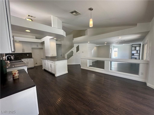 kitchen featuring dark wood-type flooring, lofted ceiling, sink, a center island, and white cabinets