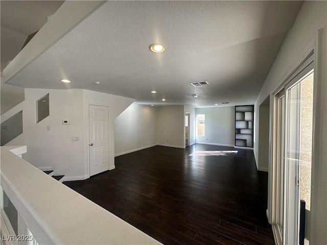 interior space featuring dark hardwood / wood-style flooring, built in features, and a textured ceiling