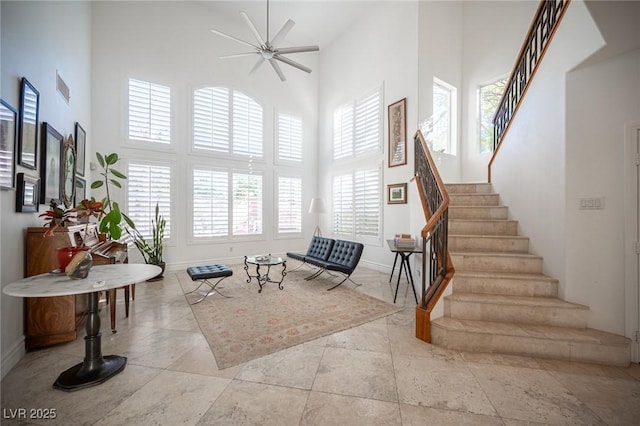 living area featuring ceiling fan and a towering ceiling