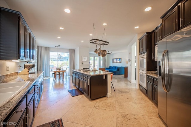 kitchen with decorative light fixtures, a center island, light stone counters, stainless steel fridge with ice dispenser, and dark brown cabinets