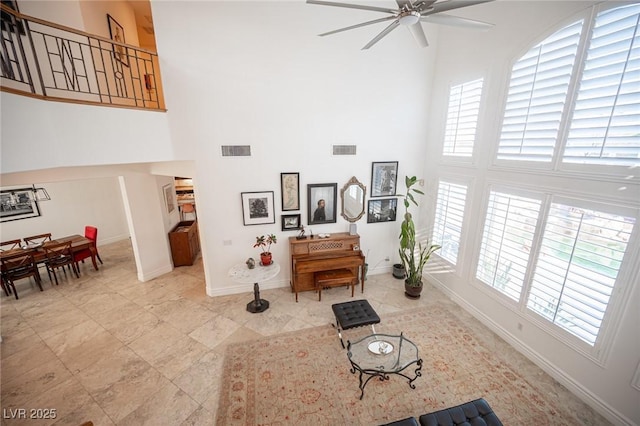 living room with ceiling fan, plenty of natural light, and a high ceiling