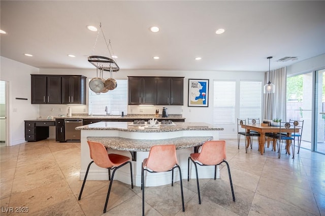 kitchen featuring pendant lighting, sink, a breakfast bar area, a kitchen island, and stainless steel dishwasher