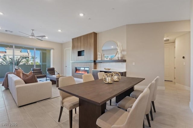 tiled dining room with a large fireplace and ceiling fan