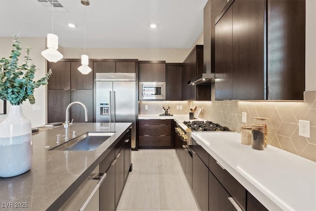 kitchen featuring sink, decorative light fixtures, dark brown cabinets, and appliances with stainless steel finishes