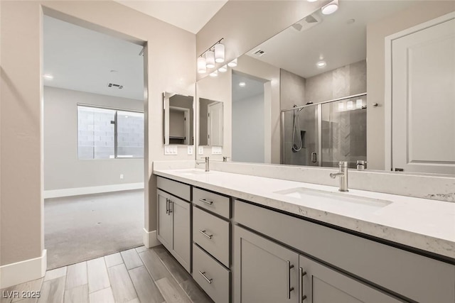 bathroom featuring double vanity, a stall shower, baseboards, and a sink