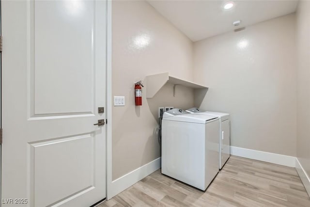 washroom with laundry area, separate washer and dryer, light wood-type flooring, and baseboards