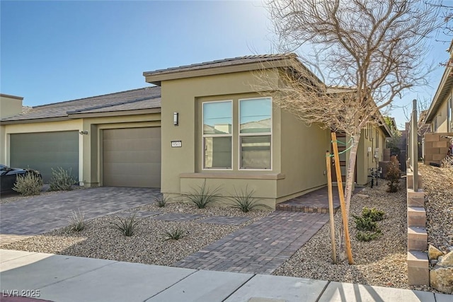 view of front of house with a garage, decorative driveway, and stucco siding