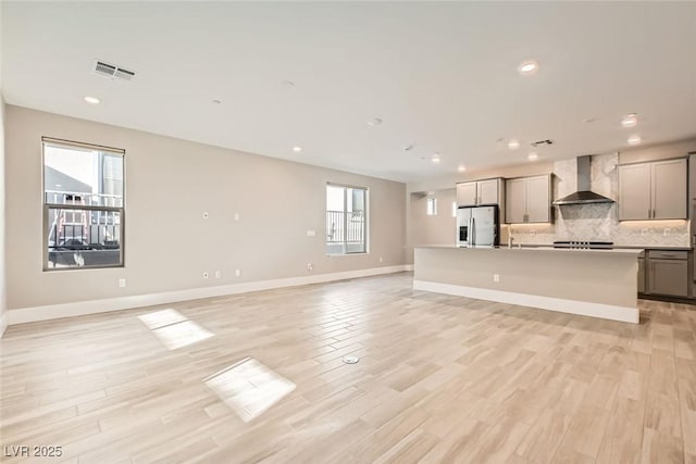 unfurnished living room with recessed lighting, visible vents, light wood-style flooring, and baseboards