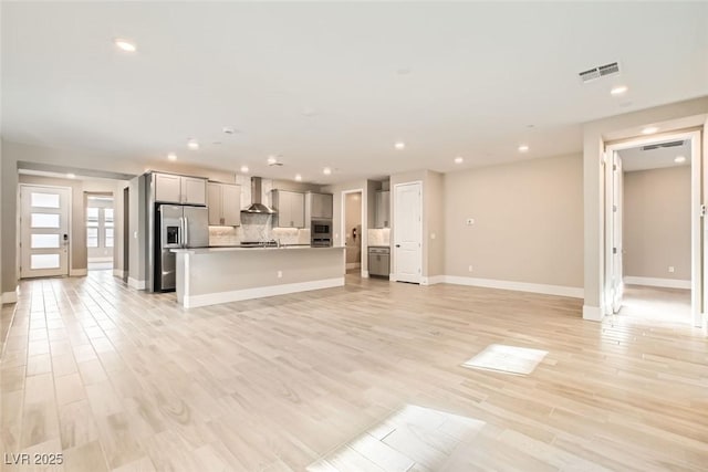 unfurnished living room with light wood-style floors, recessed lighting, visible vents, and baseboards