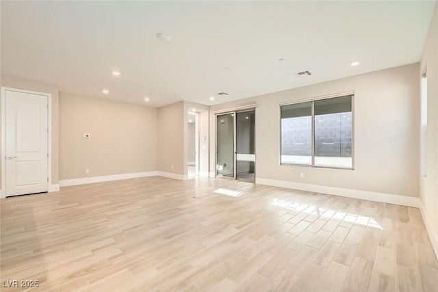 empty room featuring baseboards, visible vents, and light wood finished floors