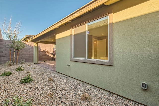 view of property exterior with a patio area, fence, and stucco siding